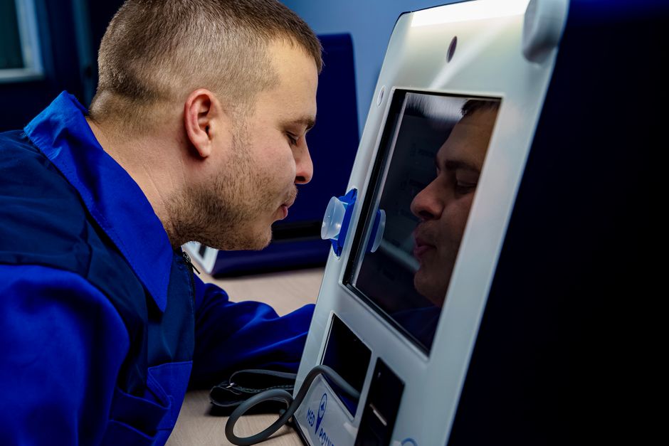A man in a blue uniform interacting with a touchscreen device indoors.