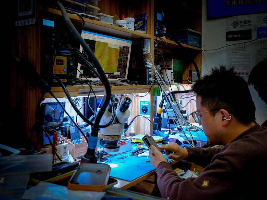 A technician diligently repairs a circuit board at a well-equipped workstation using advanced tools and equipment.