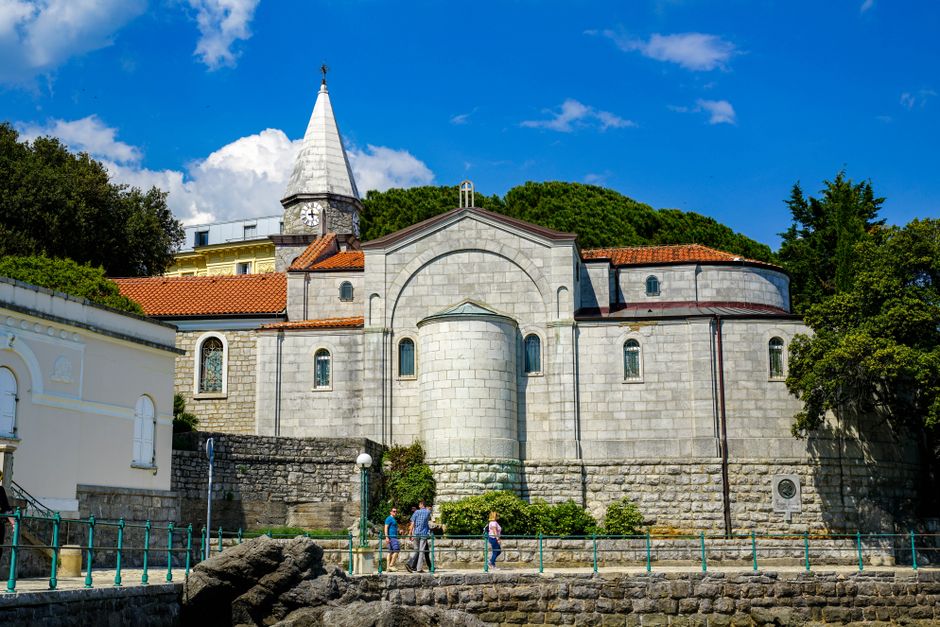 Serene view of the historic church in Opatija, Croatia, under a bright blue sky.