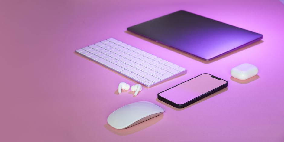 Flat lay of wireless tech gadgets on pink surface, highlighting modern electronics.
